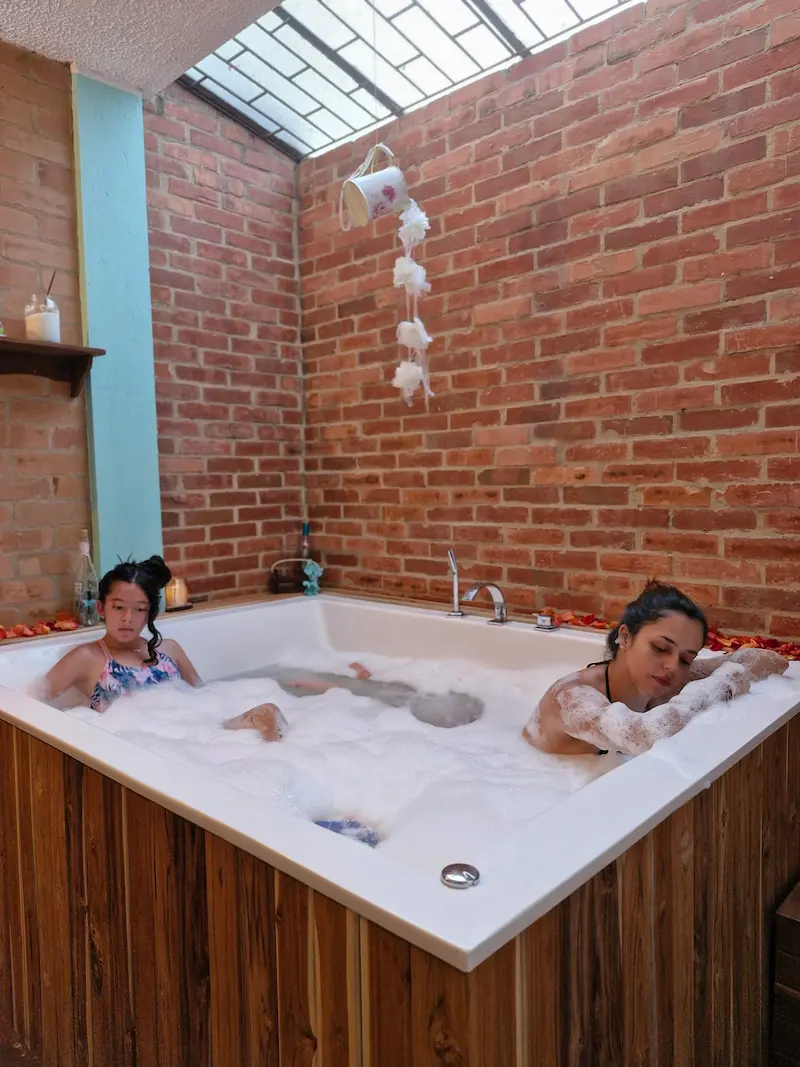 Madre e hija relajadas en el jacuzzi espumoso de Tribbu Spa
