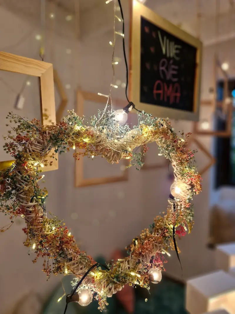 Corazón de ramas con luces junto a una pizarra con la frase «VIVE RÉ AMA» en Tribbu Spa